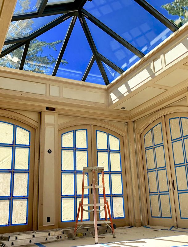 open ceiling room with skylight and fancy wood trim and french doors about to be painted